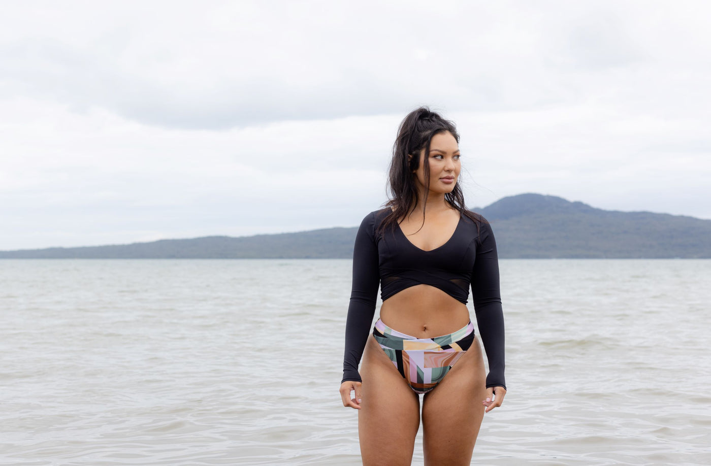 The Dip rash guard in black worn at the beach with print bikini bottoms