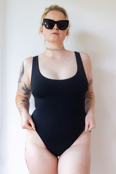 Model posing in SWMR The Dunk one piece swimsuit in black