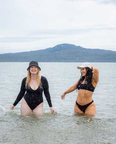 Two models in black SWMR swimwear having fun at the beach